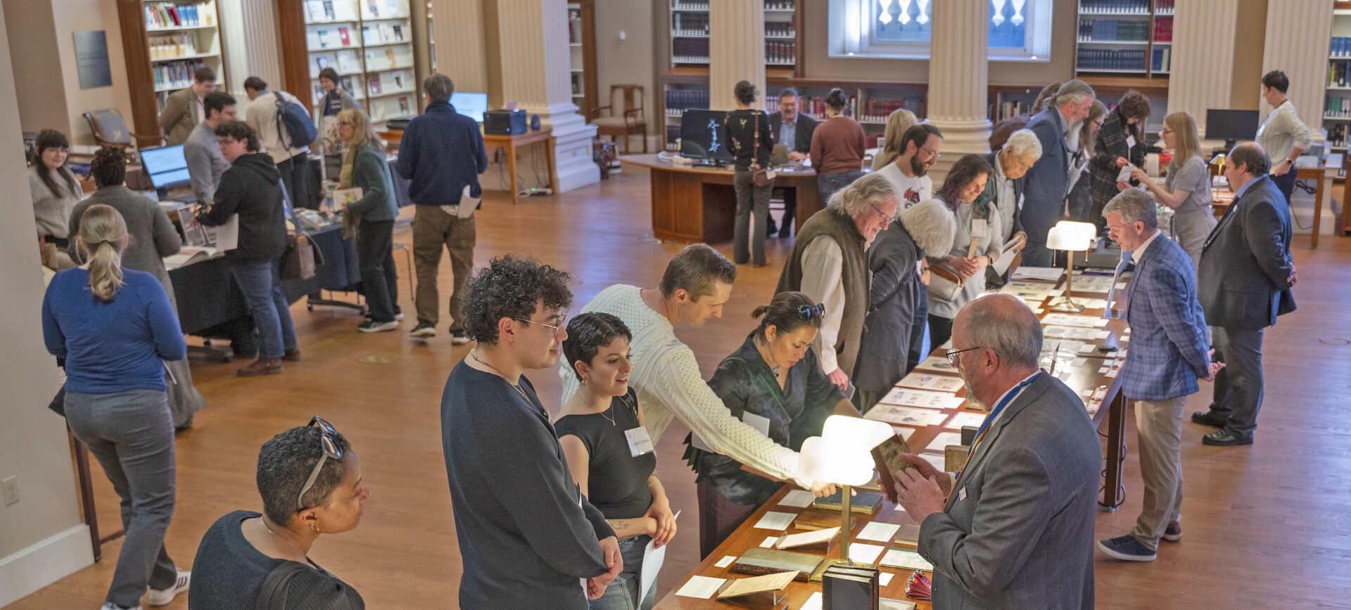 visitors and librarians looking at book and archive exhibits on a long table