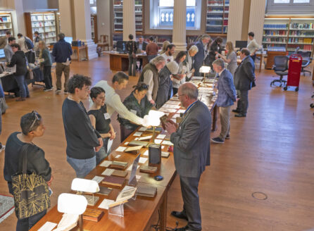 visitors and librarians looking at book and archive exhibits on a long table