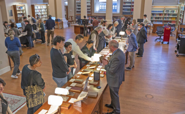 visitors and librarians looking at book and archive exhibits on a long table