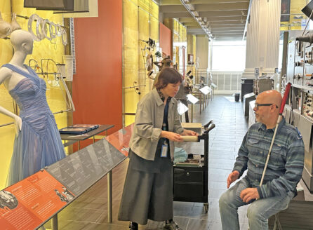 Museum educator Laura Prewitt speaks out the nylon exhibit with a man who using a white cane.