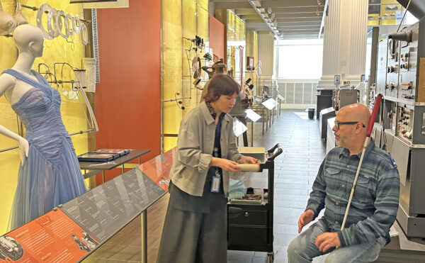 Museum educator Laura Prewitt speaks out the nylon exhibit with a man who using a white cane.