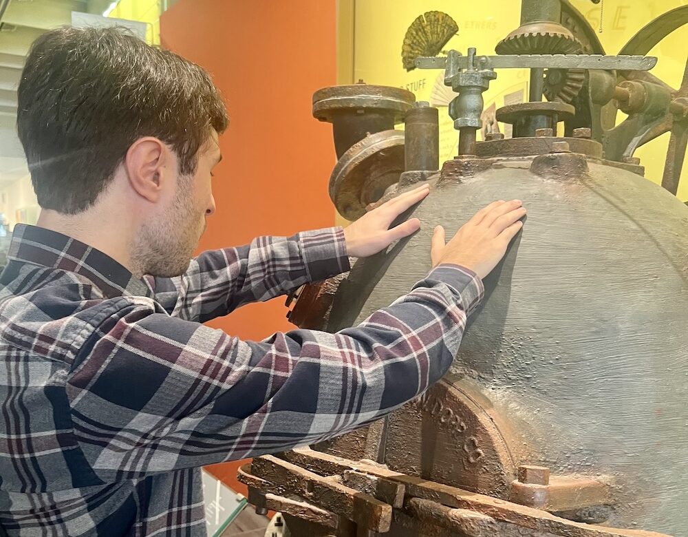 man touching a museum object with both hands