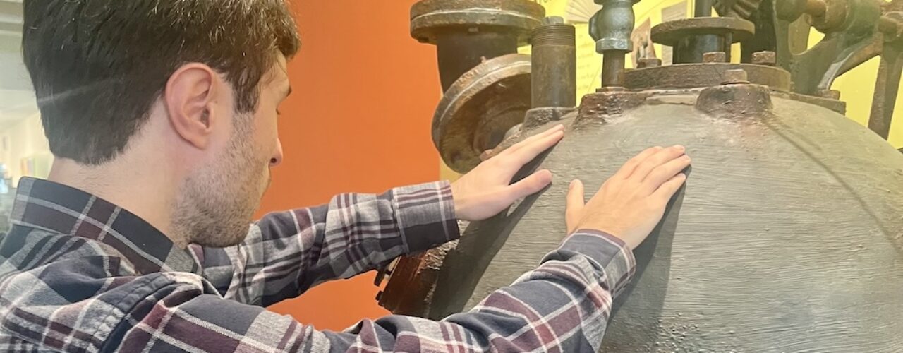 man touching a museum object with both hands