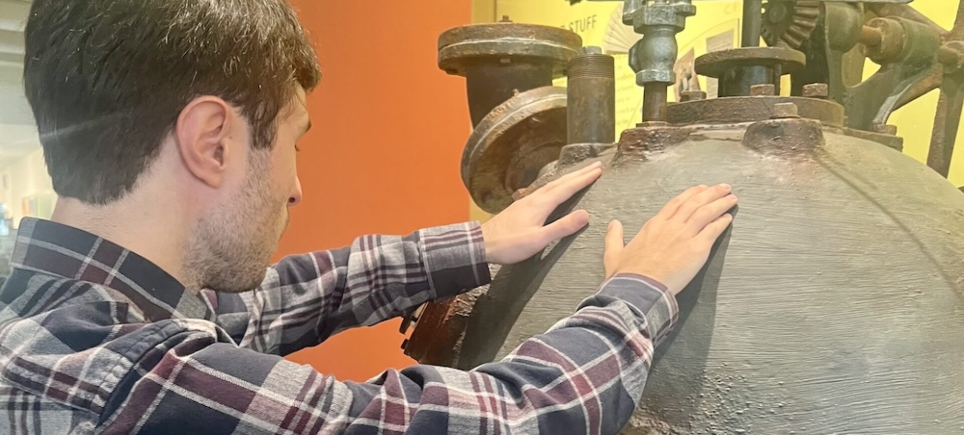man touching a museum object with both hands