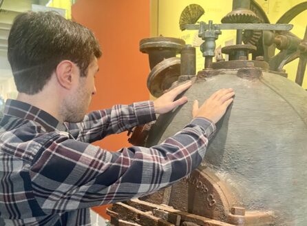 man touching a museum object with both hands