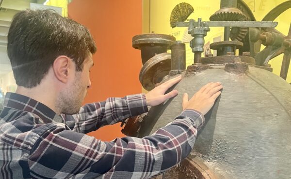 man touching a museum object with both hands
