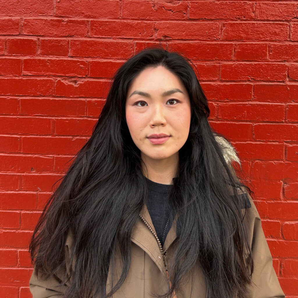 Won Jeon in front of a painted red brick wall