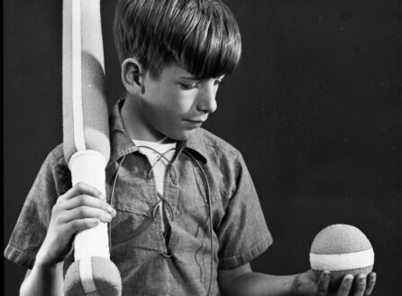 black and white photo of a boy with baseball bat and ball