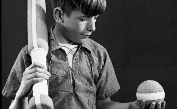 black and white photo of a boy with baseball bat and ball