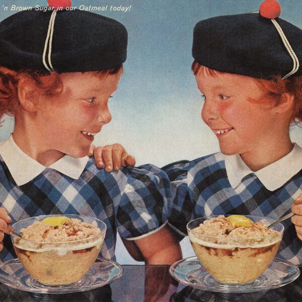 Twin girls in Scottish costumes eating bowls of oatmeal at a table