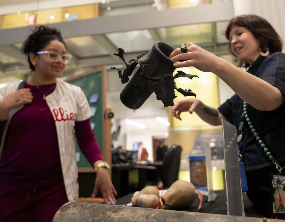 a museum educator explains what a flowerpot is to a fireworks exhibition visitor at the Science History Institute