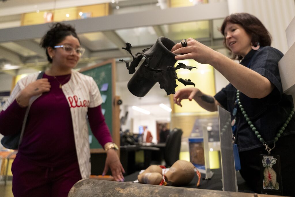 a museum educator explains what a flowerpot is to a fireworks exhibition visitor at the Science History Institute