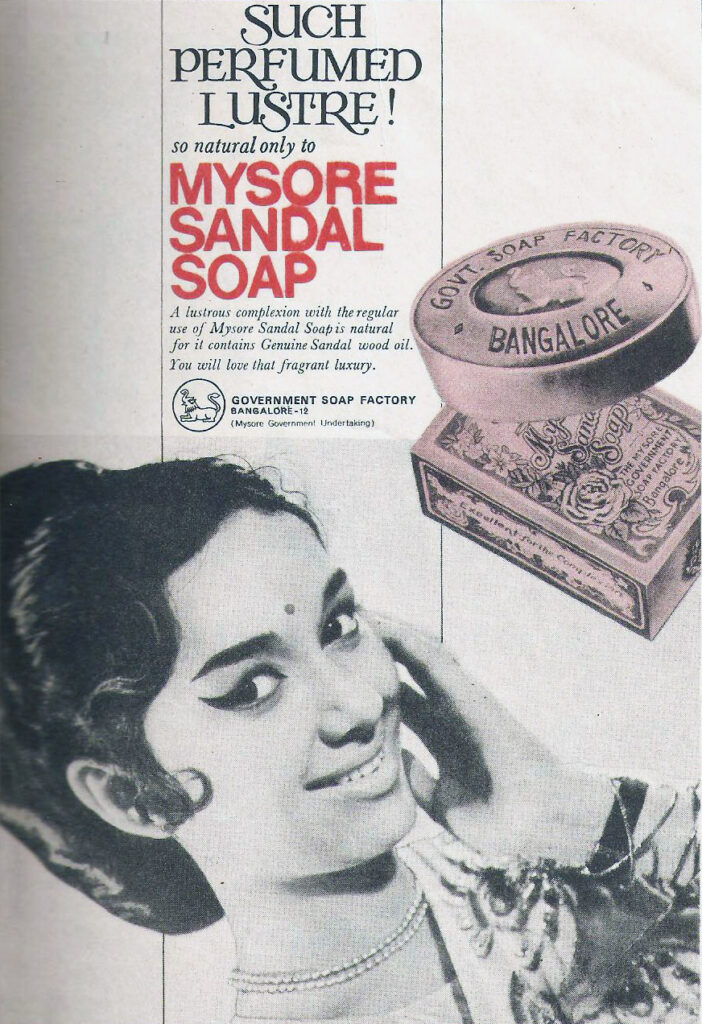 Print advertisement featuring an Indian woman smiling beside a bar of soap stamped with the words “Govt Soap Factory Bangalore.” The [tag line?] reads: “Such Perfumed Lustre!”