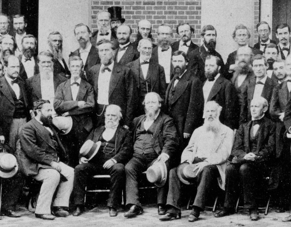 A group of men posing for a photograph in front of a house.