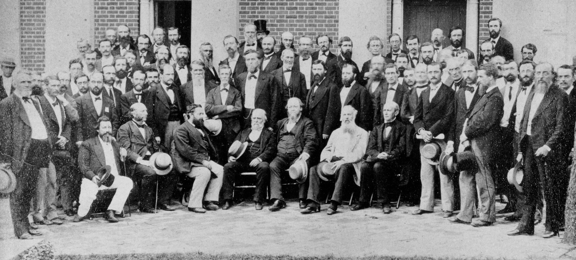 A group of men posing for a photograph in front of a house.