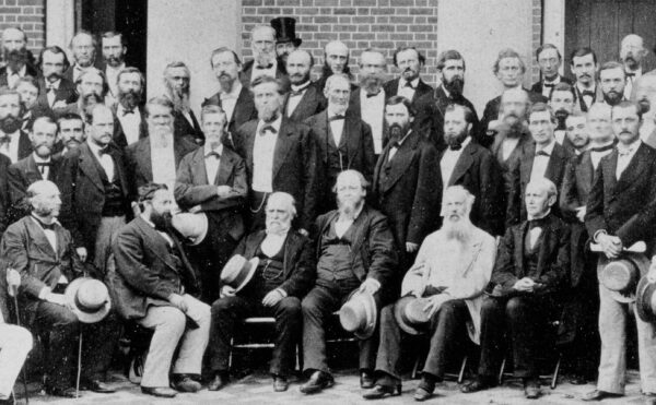 A group of men posing for a photograph in front of a house.