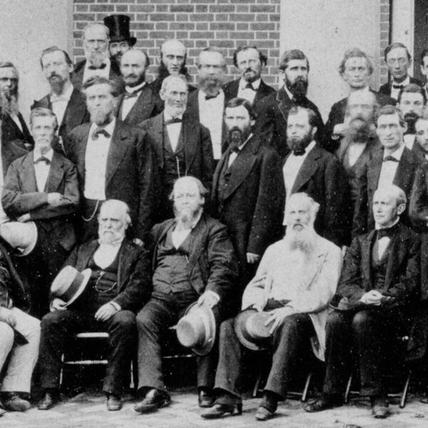 A group of men posing for a photograph in front of a house.