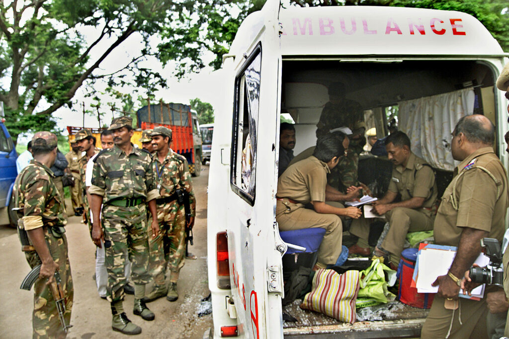 Armed men in camo and tan uniforms congregating around and sitting inside a van on a dirt road