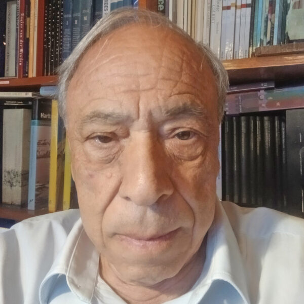 Gildo Magalhães Santos in front of a library bookshelf