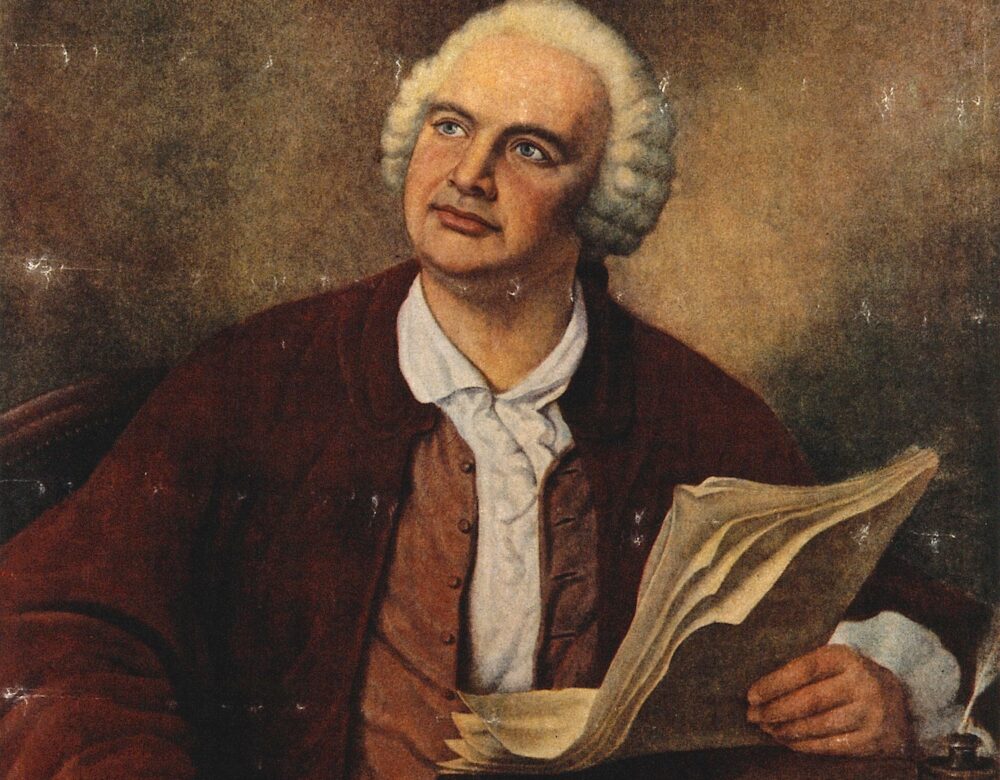 color portrait of a man seated holding a quill pen and paper