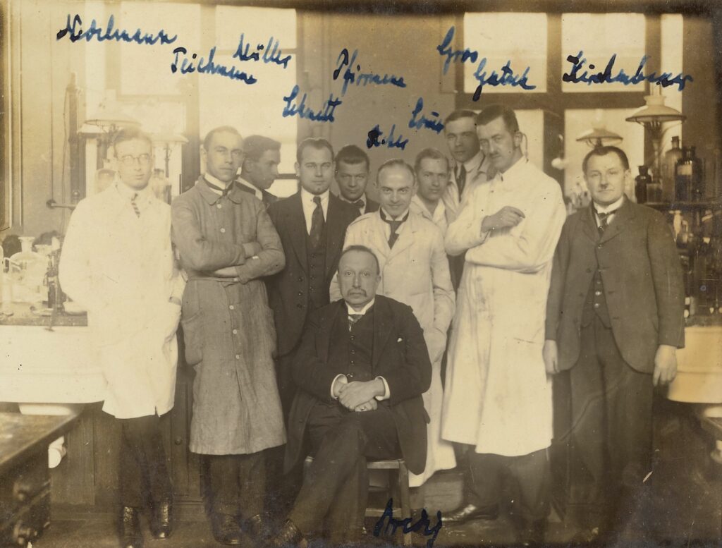 sepia-toned group photo of men in suits and lab coats