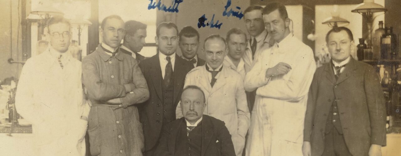 sepia-toned group photo of men in suits and lab coats