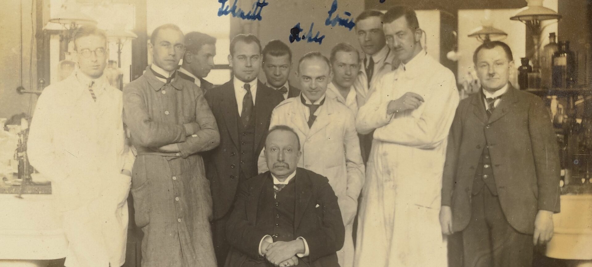 sepia-toned group photo of men in suits and lab coats