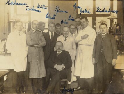 sepia-toned group photo of men in suits and lab coats