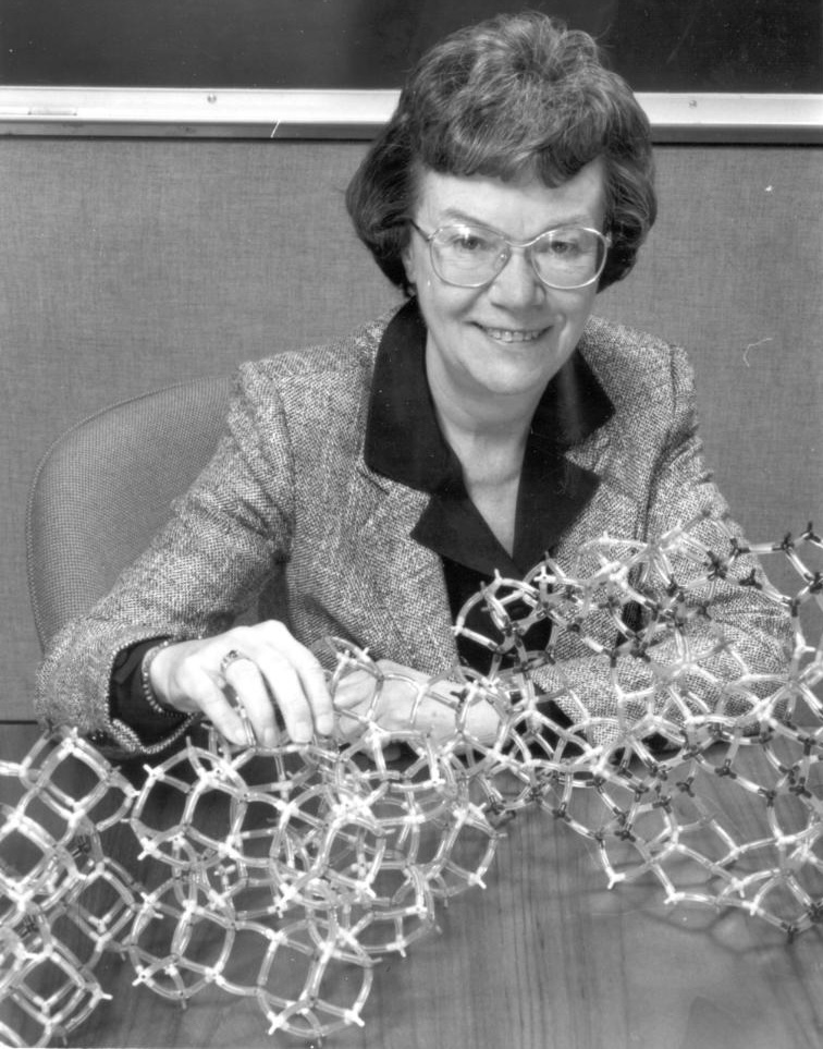 woman wearing glasses holding a model of a zeolite