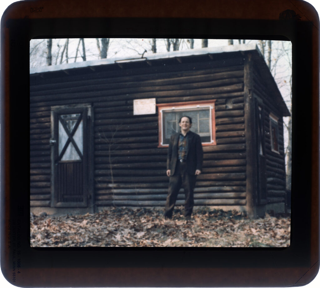 Man standing outside of a log building.