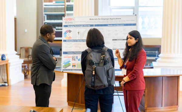 three individuals discussing a poster at Innovation Day