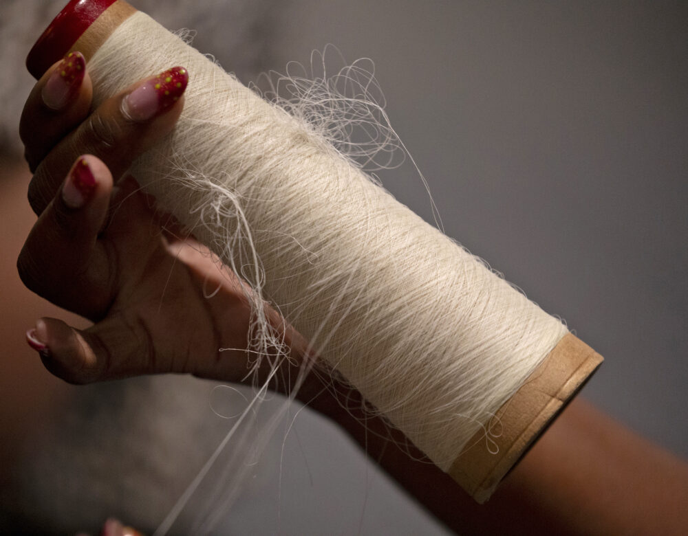 hand with manicured nails holding nylon thread in a spool