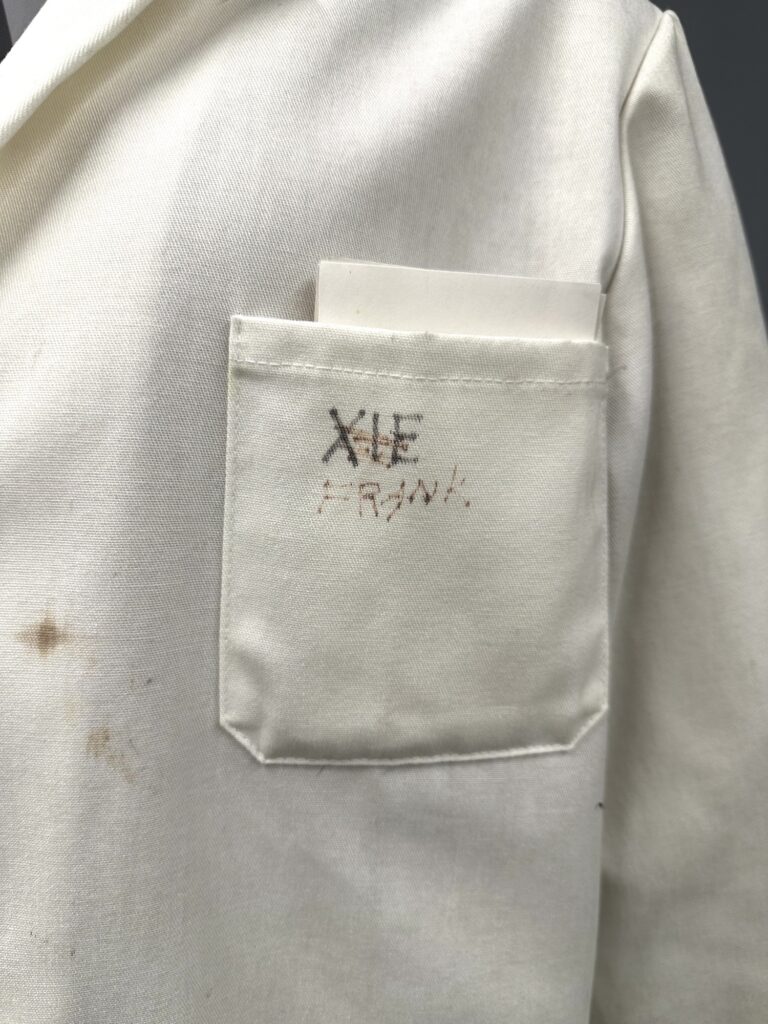 pocket of a stained lab coat marked with the names Frank and Xie crossed out