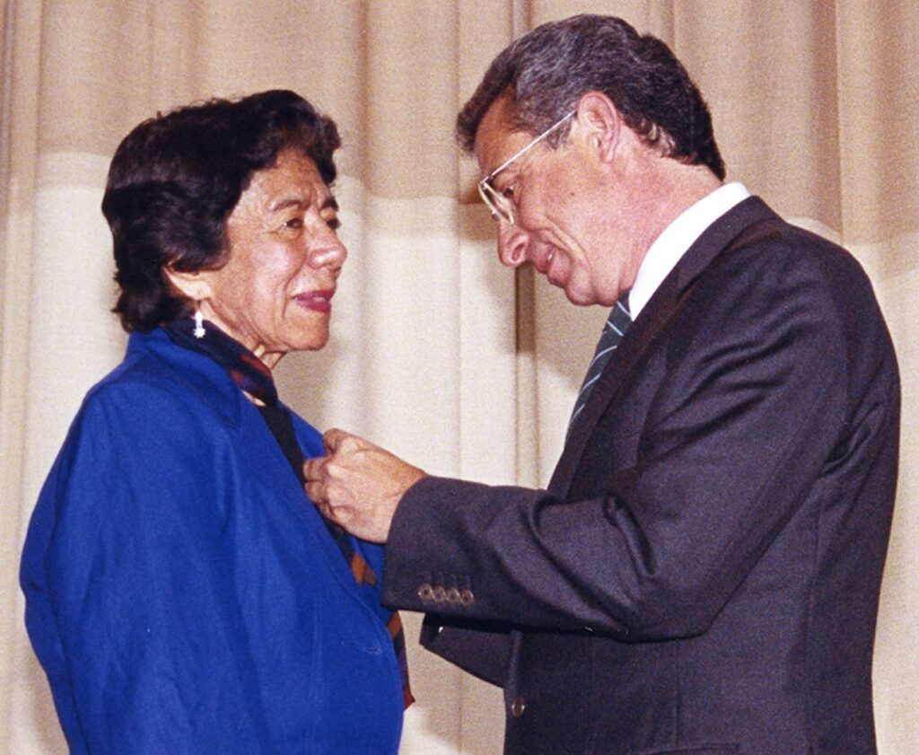 A man placing an award medal around a woman's neck