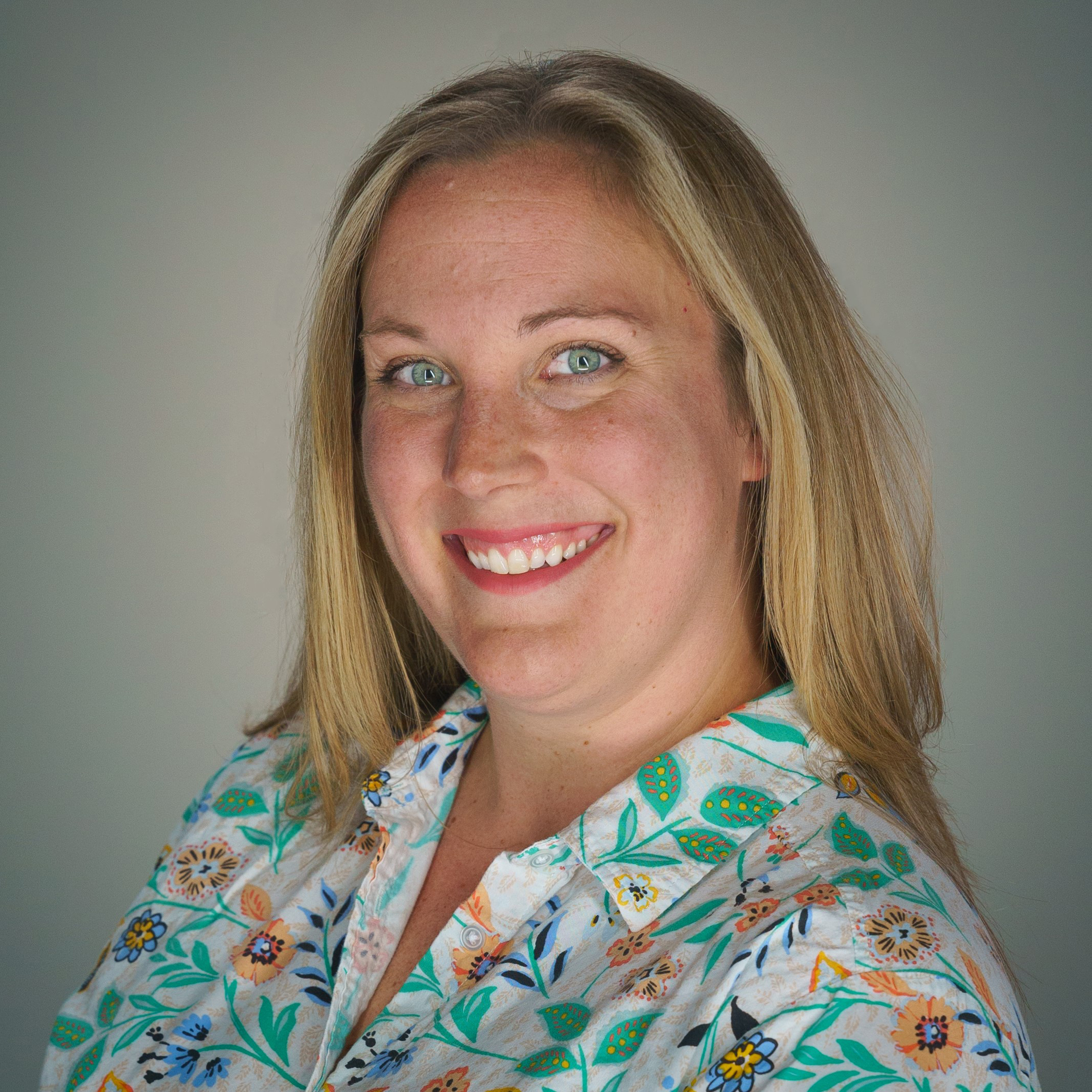 studio portrait of Lyndsay Leal, smiling, wearing a floral print shirt
