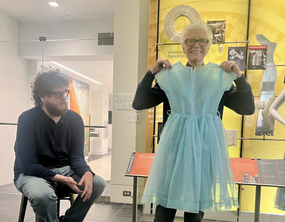 woman with glasses, standing, showing a short blue nylon dress