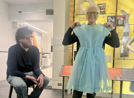 woman with glasses, standing, showing a short blue nylon dress