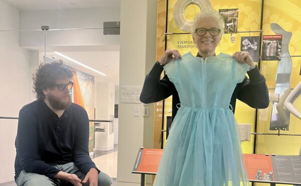 woman with glasses, standing, showing a short blue nylon dress