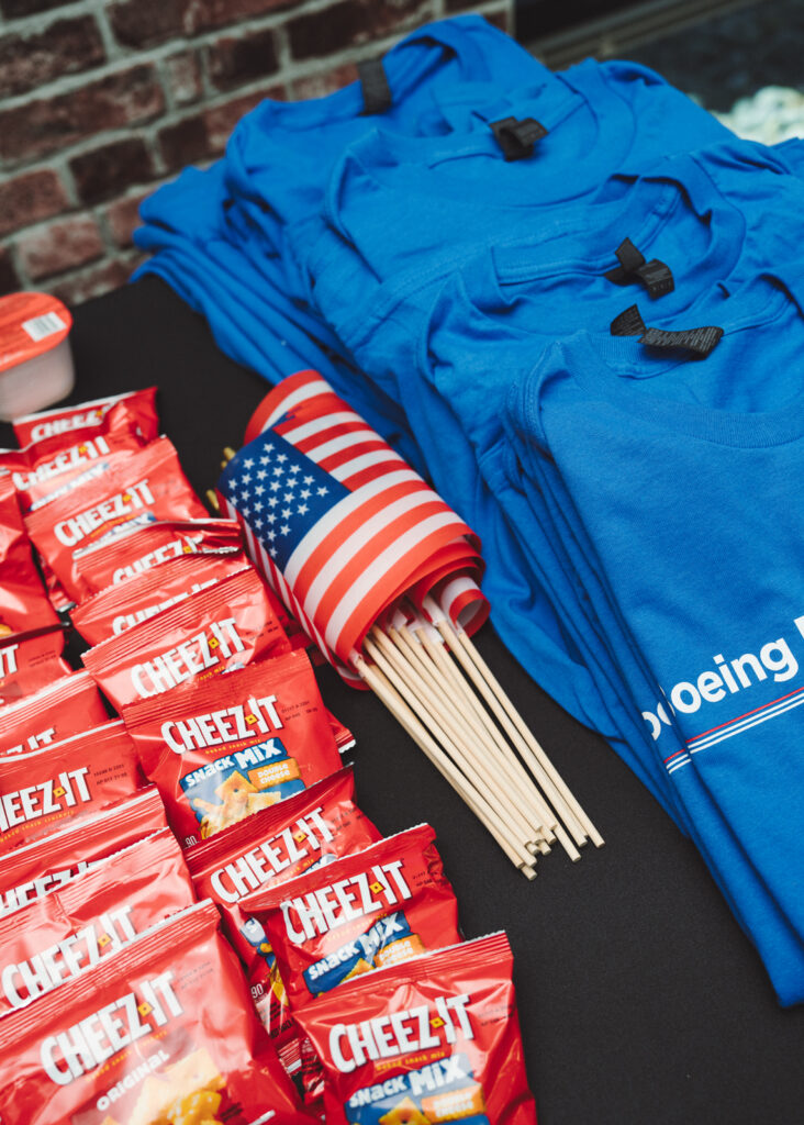 Table with Boeing-branded t-shirts, small American flags, and individual packages of Cheez-It