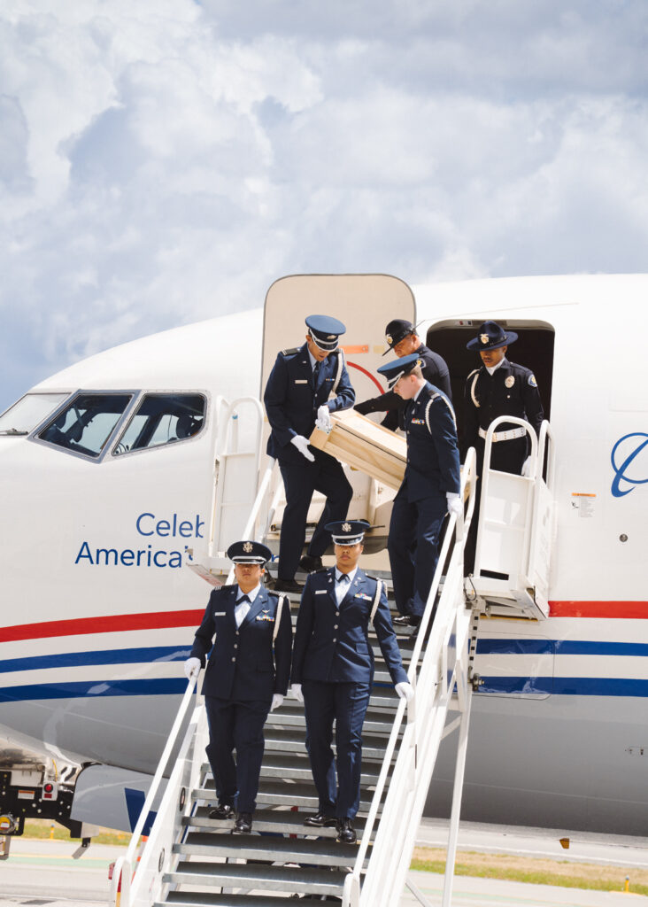 ROTC members carrying crates down a set of stairs from a jet