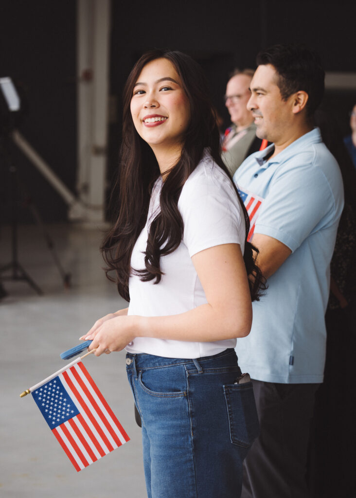 Women in hangar smiling and holding an American flag