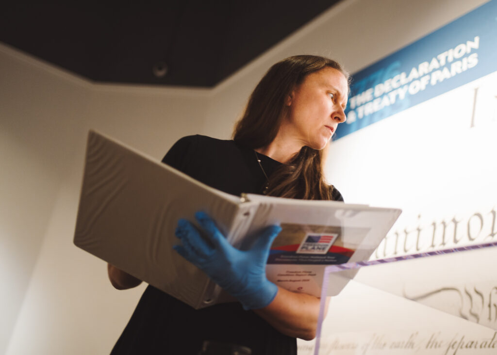 Women examining something off camera while holding a three-ringer binder