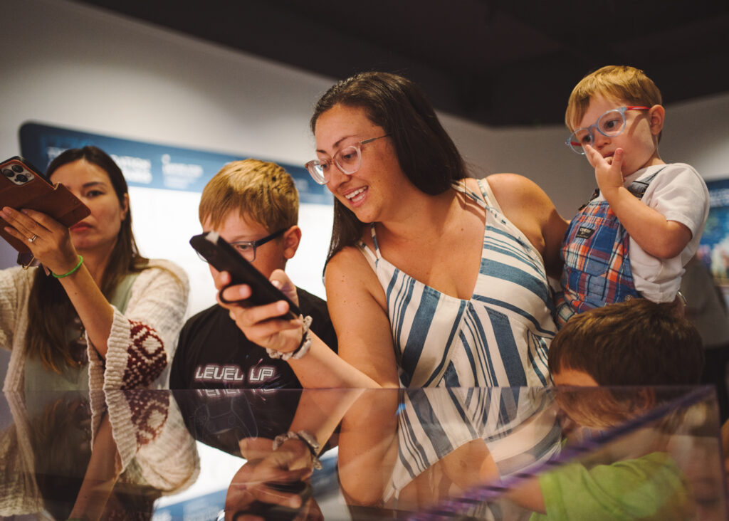 Women holding a toddler while taking a picture with a cellphone