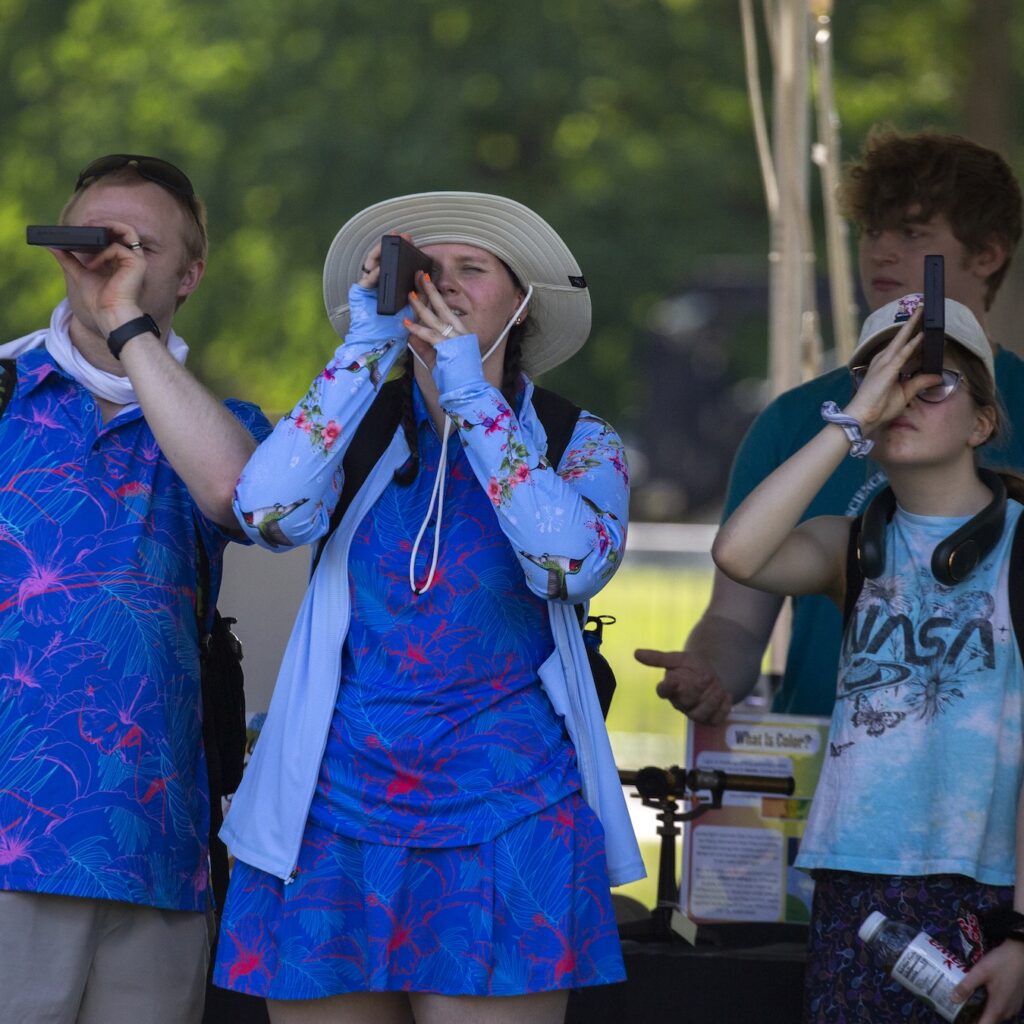 three people look at the sky using spectroscopes