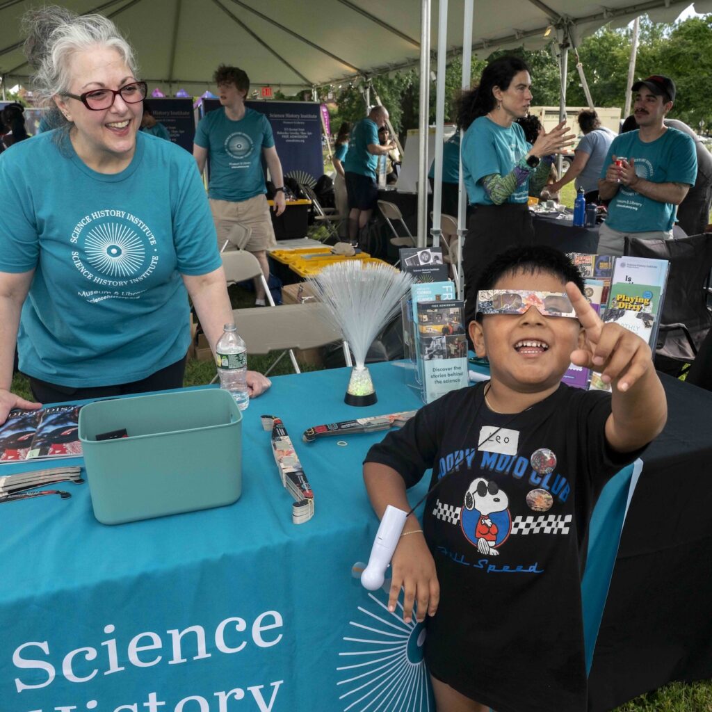 a child wearing diffraction glasses points at the sky