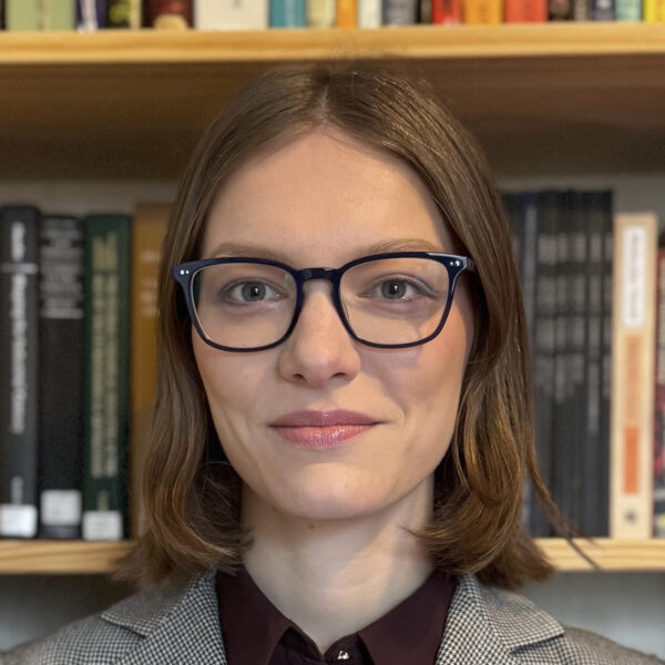 Alison McManus wearing glasses, standing in front of books