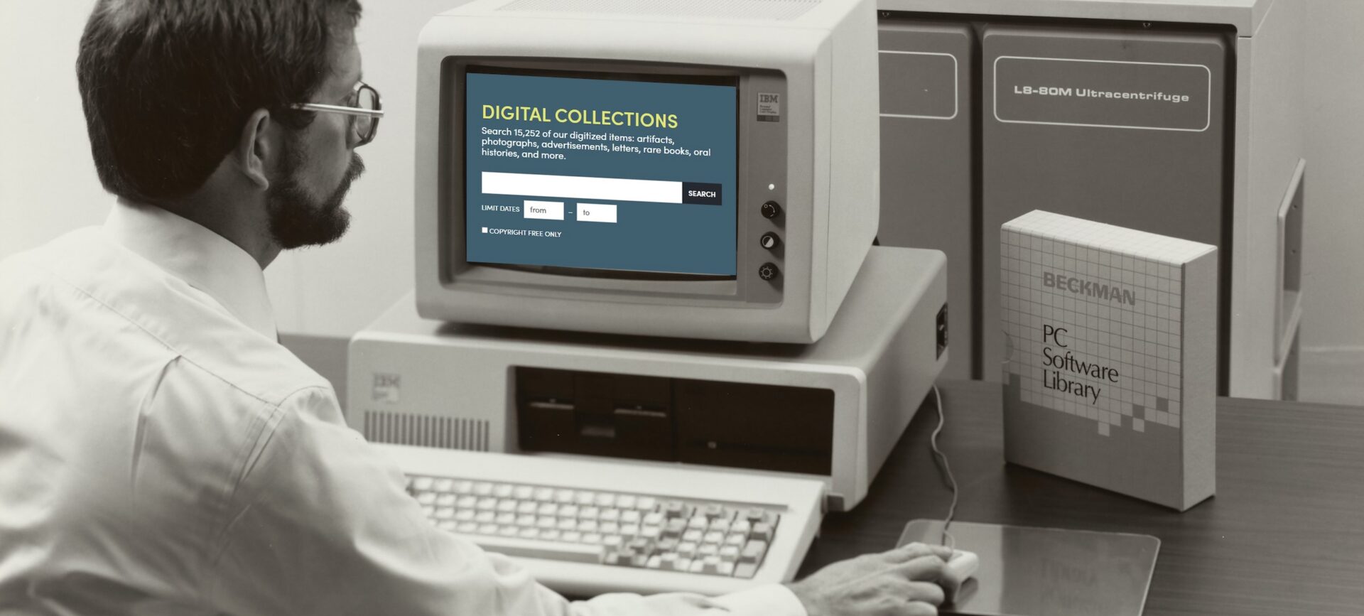 man in glasses sitting in front of a computer screen holding a mouse