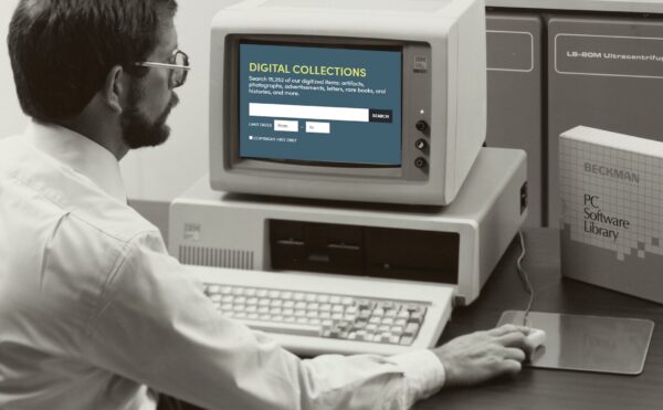 man in glasses sitting in front of a computer screen holding a mouse