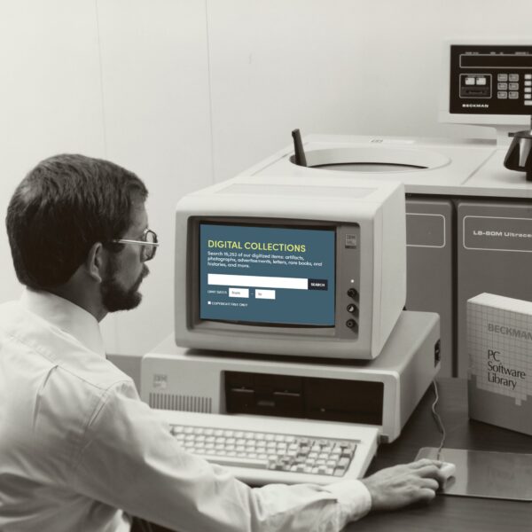 man in glasses sitting in front of a computer screen holding a mouse