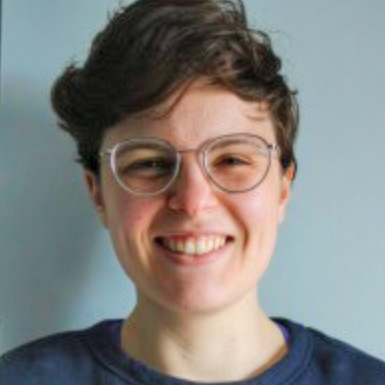 Jo D'Avella, smiling and wearing glasses